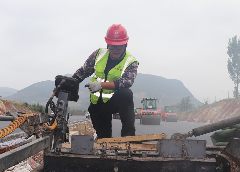 4、油層施工隊長朱紹濤根據(jù)現(xiàn)場實際微調(diào)攤鋪機控制攤鋪質(zhì)量_副本